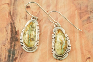Genuine Boulder Turquoise set in Sterling Silver French Wire Earrings. The cabachons are of Boulder Turquoise, you can see the veins of Turquoise running through the host rock. The Boulder Turquoise Mine is located in northeast Nevada. It was discovered in 1970 by a Shoshone sheep herder. Production is small due to the remote location and winter weather. Boulder Turquoise is valued for both it's beauty and rarity. Every stone is unique. Created by Navajo Artist Larson Lee. Signed by the artist.